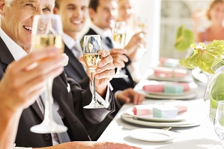 Guests Holding Champagne Flutes While Sitting At Table