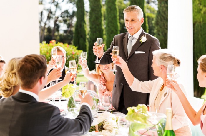 Father Toasting Champagne With Guests And Couple At Table