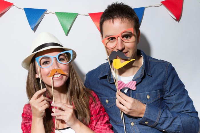 Young couple in a Photo Booth party with garland decoration background